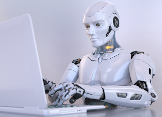 A white humanoid robot typing on a laptop.
